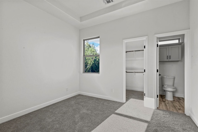 carpeted bedroom with ensuite bath and a spacious closet