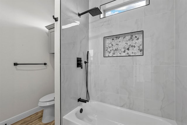 bathroom featuring wood-type flooring, tiled shower / bath, and toilet