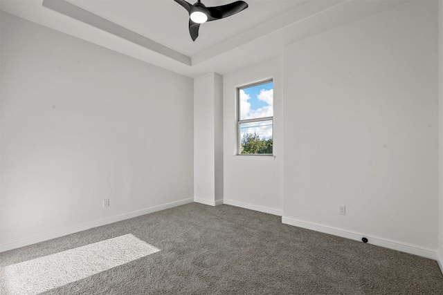 spare room with ceiling fan, a raised ceiling, and carpet