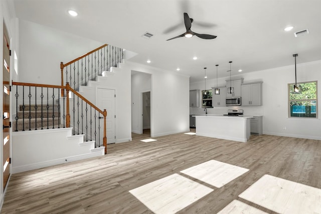 unfurnished living room with light wood-type flooring, crown molding, and ceiling fan