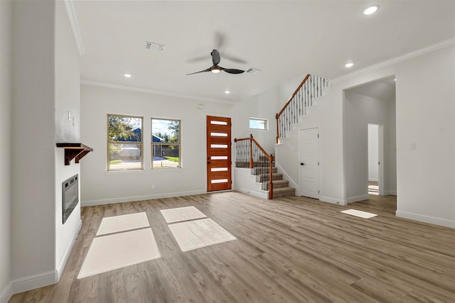 unfurnished living room featuring ornamental molding, light wood-type flooring, and ceiling fan