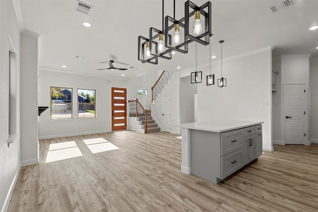 kitchen featuring ornamental molding, decorative light fixtures, light hardwood / wood-style flooring, gray cabinets, and a center island