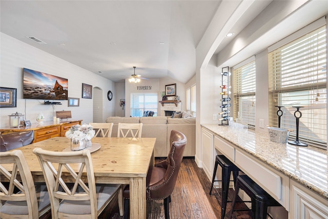 dining area with ceiling fan, a fireplace, and dark wood-type flooring