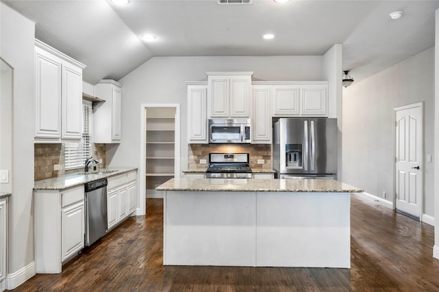 kitchen featuring a sink, stainless steel appliances, lofted ceiling, and white cabinets