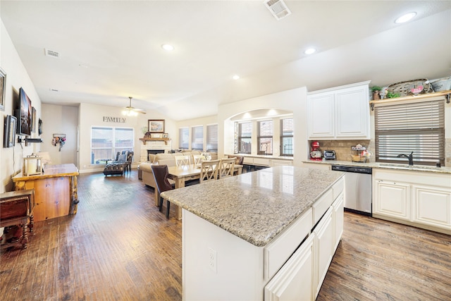 kitchen featuring dishwasher, sink, vaulted ceiling, a kitchen island, and white cabinetry