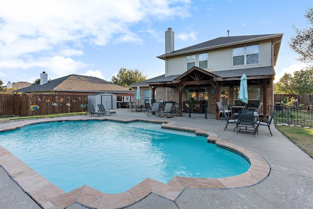 view of pool with a storage shed and a patio