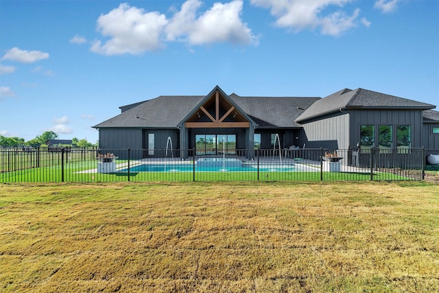 back of property with a yard and a fenced in pool