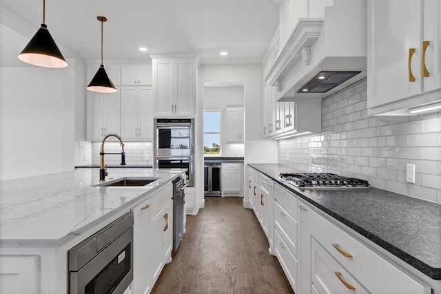 kitchen featuring pendant lighting, sink, white cabinets, appliances with stainless steel finishes, and premium range hood