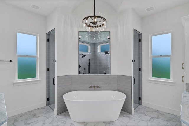 bathroom with separate shower and tub, a chandelier, and a healthy amount of sunlight