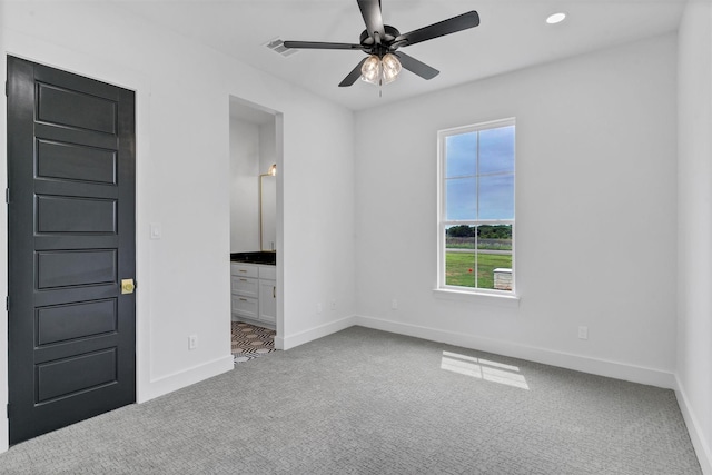 unfurnished bedroom with ceiling fan, carpet floors, and ensuite bathroom