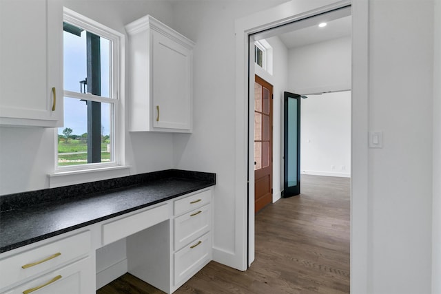 kitchen featuring white cabinets, built in desk, and dark hardwood / wood-style floors