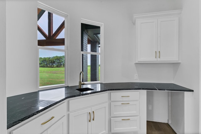 kitchen featuring dark stone counters, a wealth of natural light, white cabinetry, and dark wood-type flooring