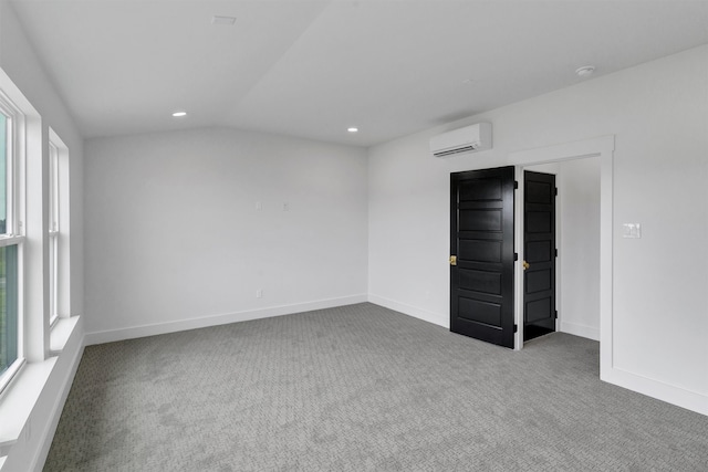 empty room with vaulted ceiling, carpet, and a wall mounted AC