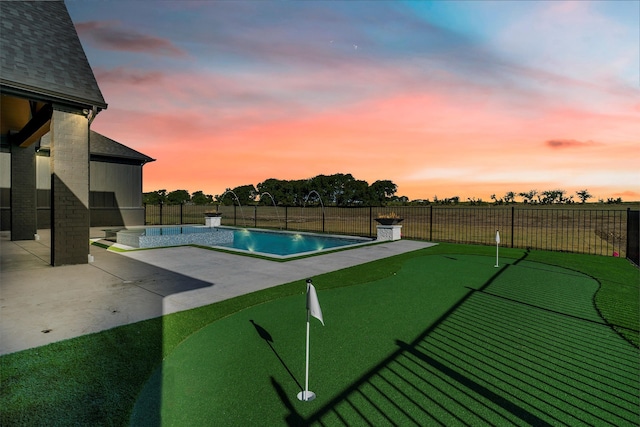 pool at dusk featuring a patio and pool water feature