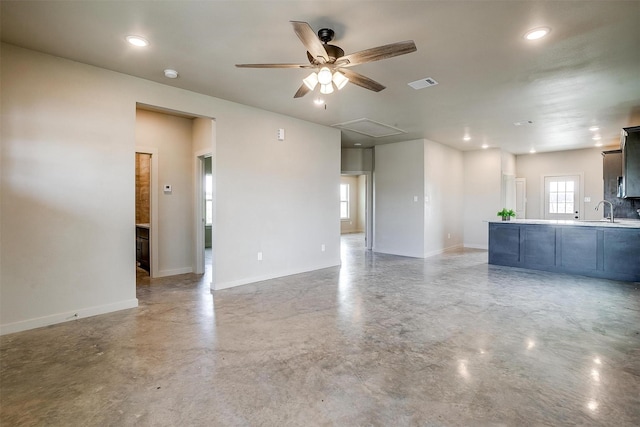 unfurnished living room featuring ceiling fan, concrete flooring, and sink