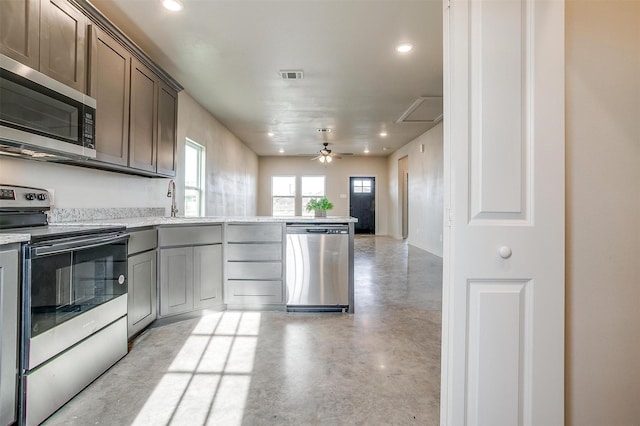 kitchen with ceiling fan, kitchen peninsula, sink, and stainless steel appliances