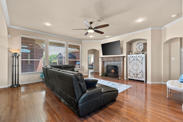 living room featuring a fireplace, hardwood / wood-style floors, ceiling fan, and ornamental molding