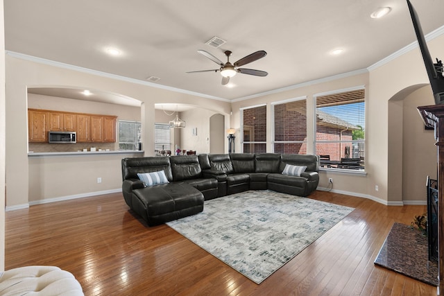 living room featuring hardwood / wood-style floors, ceiling fan with notable chandelier, and ornamental molding