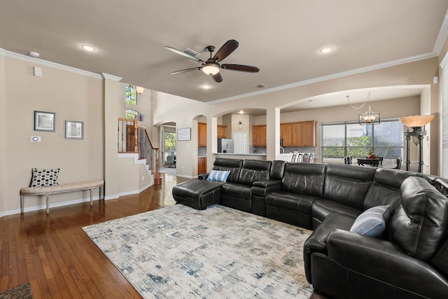 living room featuring ceiling fan with notable chandelier, dark hardwood / wood-style flooring, and crown molding