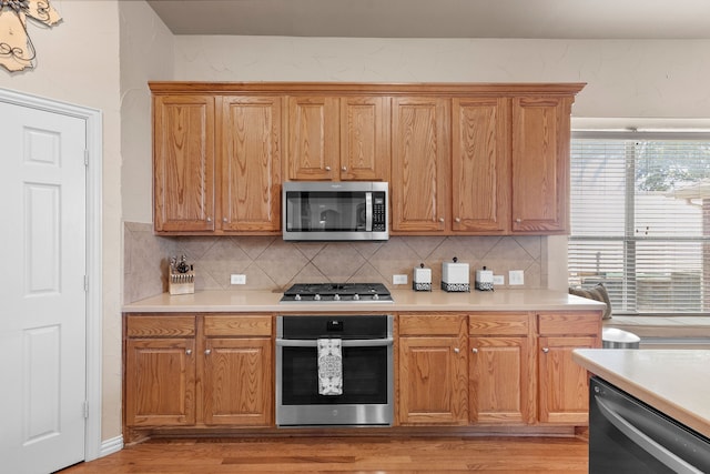 kitchen featuring appliances with stainless steel finishes, backsplash, and light hardwood / wood-style floors