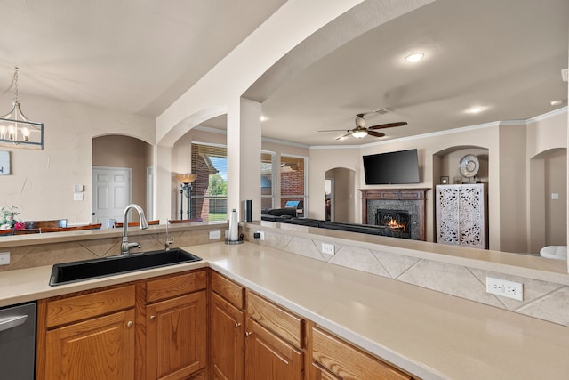 kitchen with sink, stainless steel dishwasher, crown molding, pendant lighting, and ceiling fan with notable chandelier