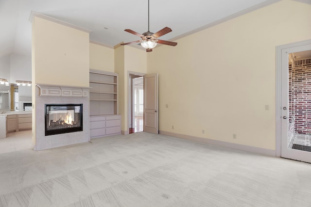 unfurnished living room featuring ceiling fan, crown molding, high vaulted ceiling, a multi sided fireplace, and light colored carpet