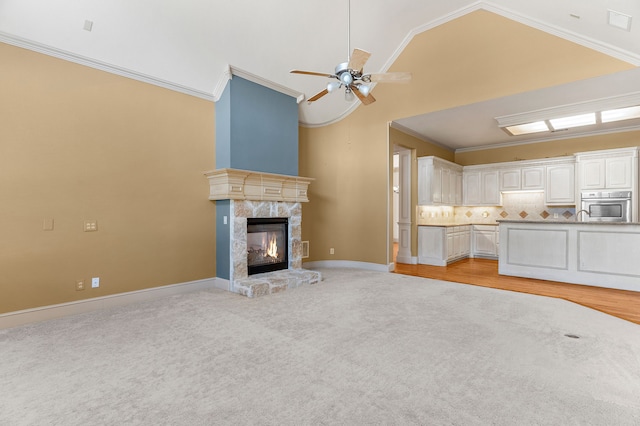 unfurnished living room with ceiling fan, high vaulted ceiling, ornamental molding, and light colored carpet