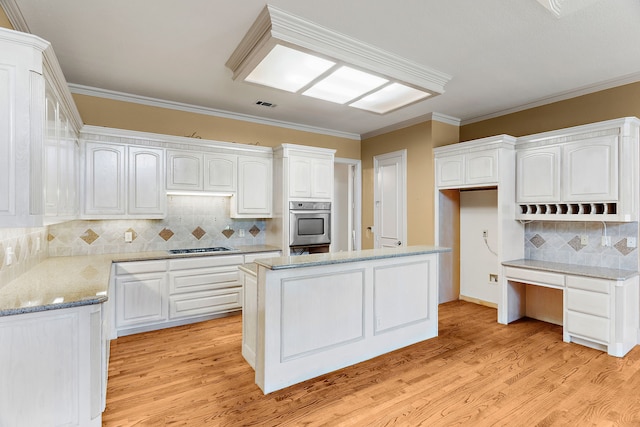 kitchen featuring crown molding, light hardwood / wood-style flooring, a kitchen island, and white cabinets