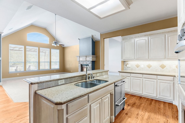 kitchen with lofted ceiling, an island with sink, light hardwood / wood-style flooring, sink, and ceiling fan