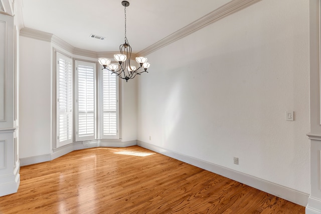 unfurnished room featuring crown molding, light hardwood / wood-style flooring, an inviting chandelier, and plenty of natural light