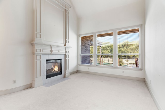 unfurnished living room with vaulted ceiling, light carpet, and a tiled fireplace