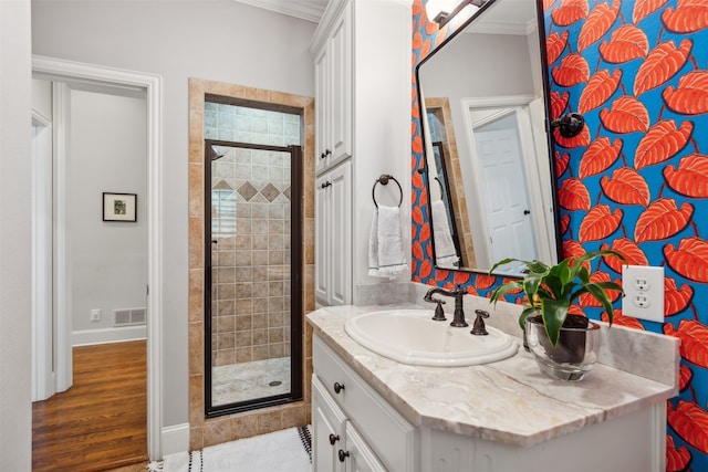 bathroom featuring ornamental molding, wood-type flooring, walk in shower, and vanity