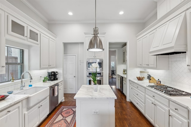 kitchen featuring appliances with stainless steel finishes, white cabinetry, a kitchen island, decorative light fixtures, and premium range hood