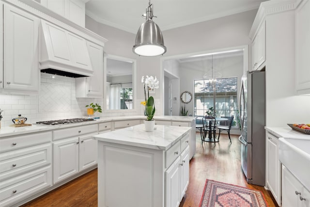 kitchen with stainless steel appliances, white cabinets, hardwood / wood-style flooring, and a kitchen island