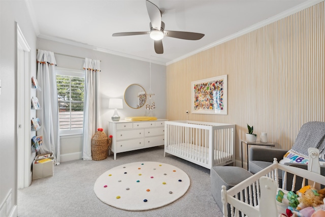 bedroom with a crib, crown molding, carpet, and ceiling fan