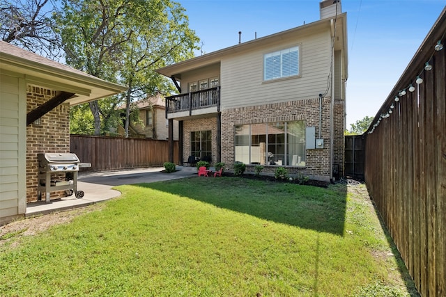 rear view of property with a lawn, a patio, and a balcony