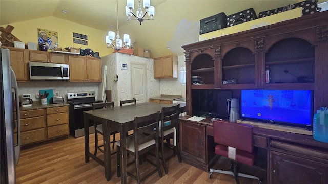 kitchen with appliances with stainless steel finishes, vaulted ceiling, dark hardwood / wood-style flooring, decorative light fixtures, and a chandelier