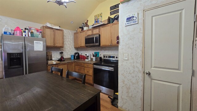 kitchen with light hardwood / wood-style flooring, stainless steel appliances, and vaulted ceiling