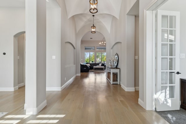 entrance foyer with vaulted ceiling, light hardwood / wood-style flooring, and a chandelier