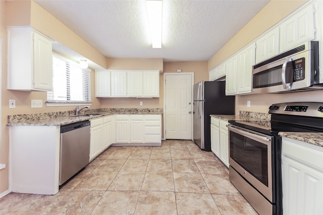 kitchen featuring a textured ceiling, sink, white cabinetry, appliances with stainless steel finishes, and light tile patterned floors