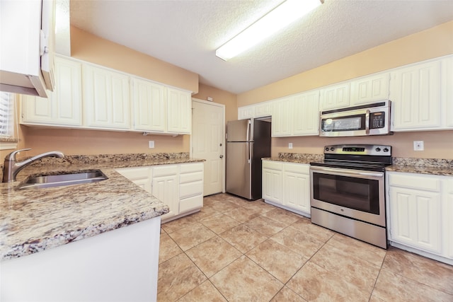 kitchen featuring a textured ceiling, sink, white cabinetry, stainless steel appliances, and light tile patterned floors