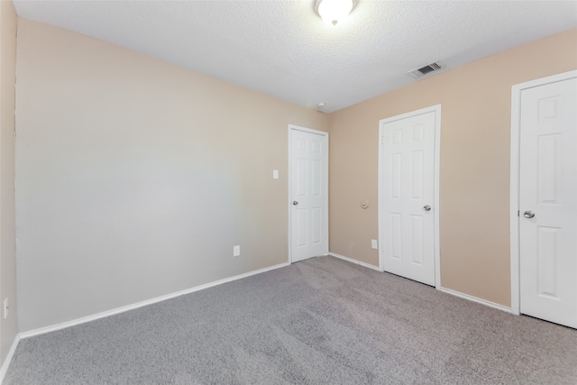 unfurnished bedroom with a textured ceiling and carpet flooring