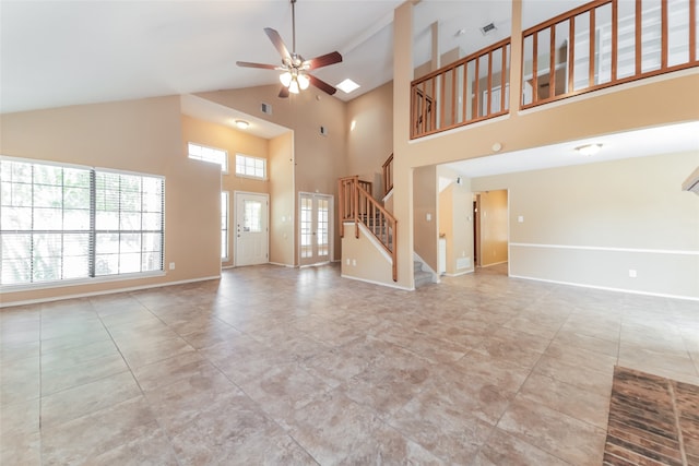 unfurnished living room with light tile patterned floors, ceiling fan, a skylight, and high vaulted ceiling