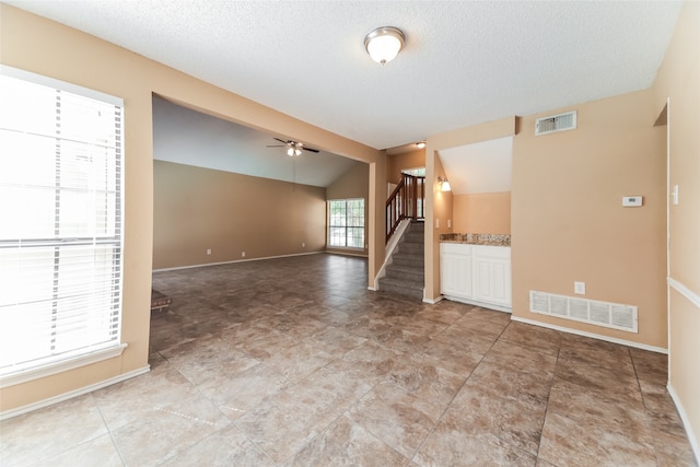 unfurnished room with ceiling fan, a textured ceiling, and lofted ceiling