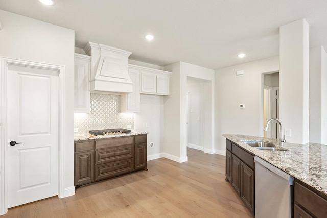 kitchen featuring dishwasher, dark brown cabinets, sink, and light hardwood / wood-style flooring