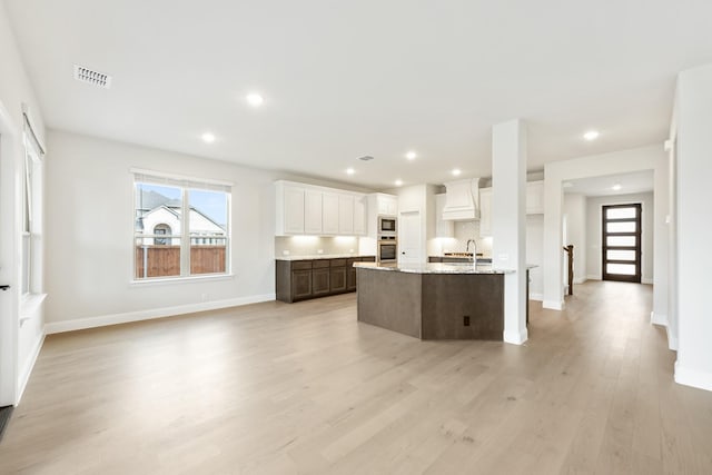 kitchen with dark brown cabinetry, built in microwave, decorative backsplash, white cabinets, and custom exhaust hood