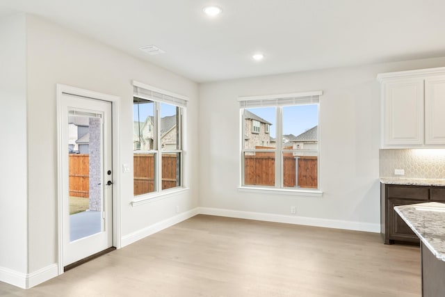 unfurnished dining area featuring light hardwood / wood-style floors and plenty of natural light