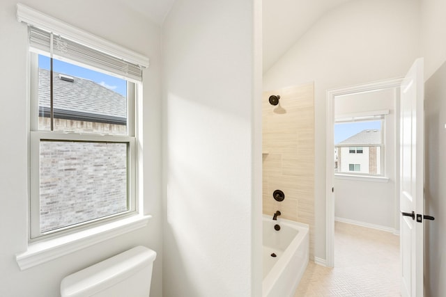 bathroom featuring a healthy amount of sunlight, toilet, lofted ceiling, and bathing tub / shower combination