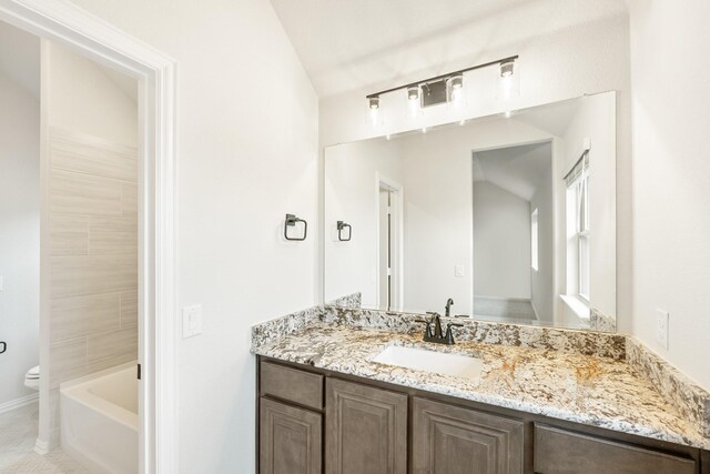 bathroom with tile patterned flooring, vanity, vaulted ceiling, and toilet