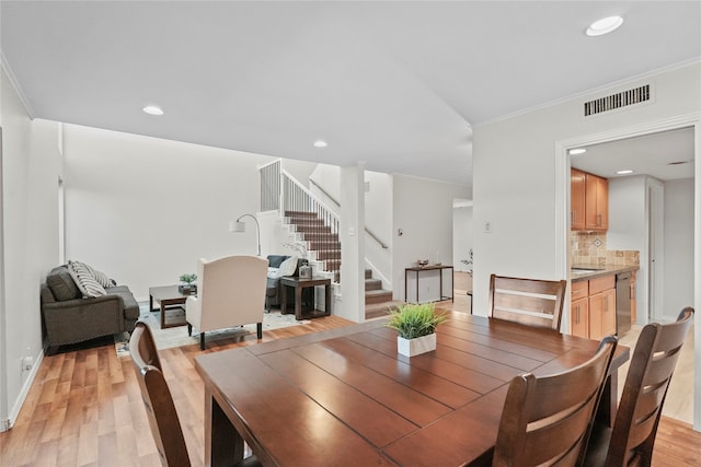 dining room with light hardwood / wood-style flooring and crown molding